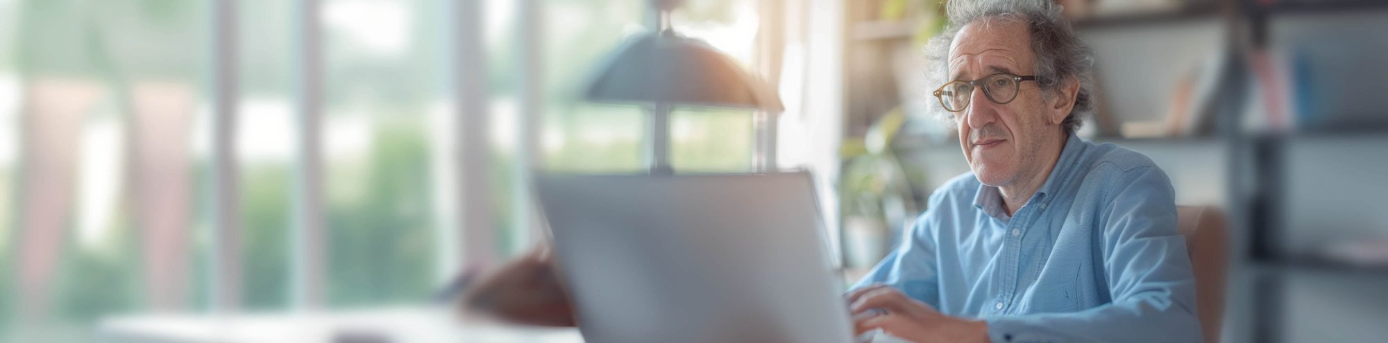 Dottore in camicia seduto davanti a un laptop.