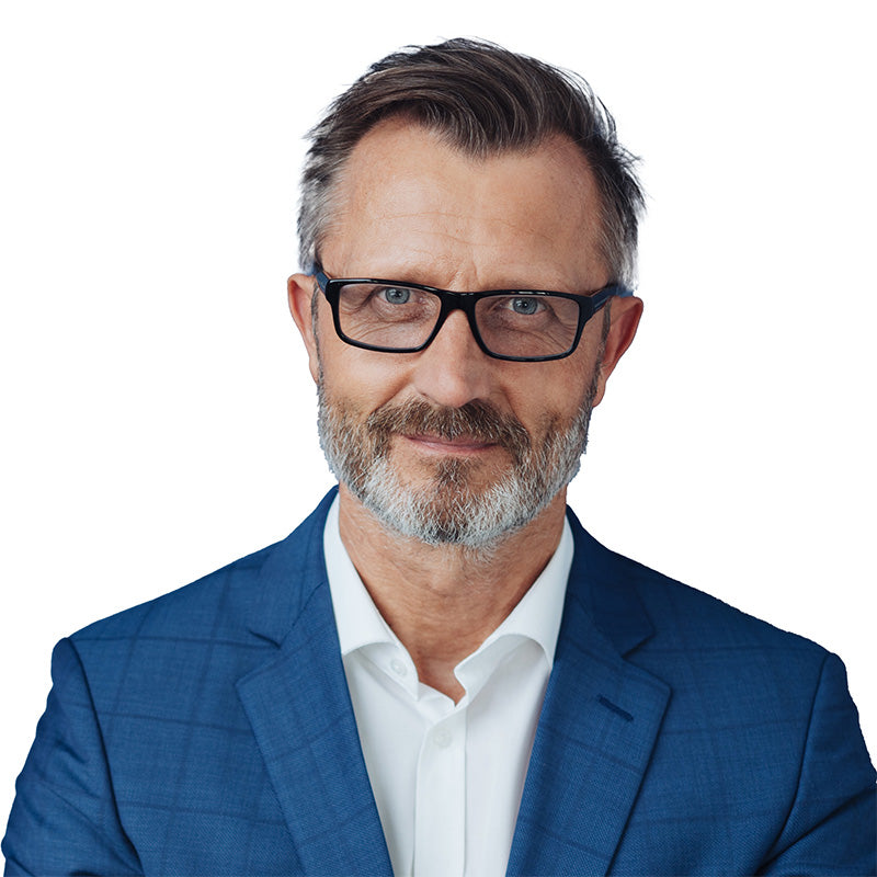 Medico di mezza età in abito professionale con sorriso leggero.